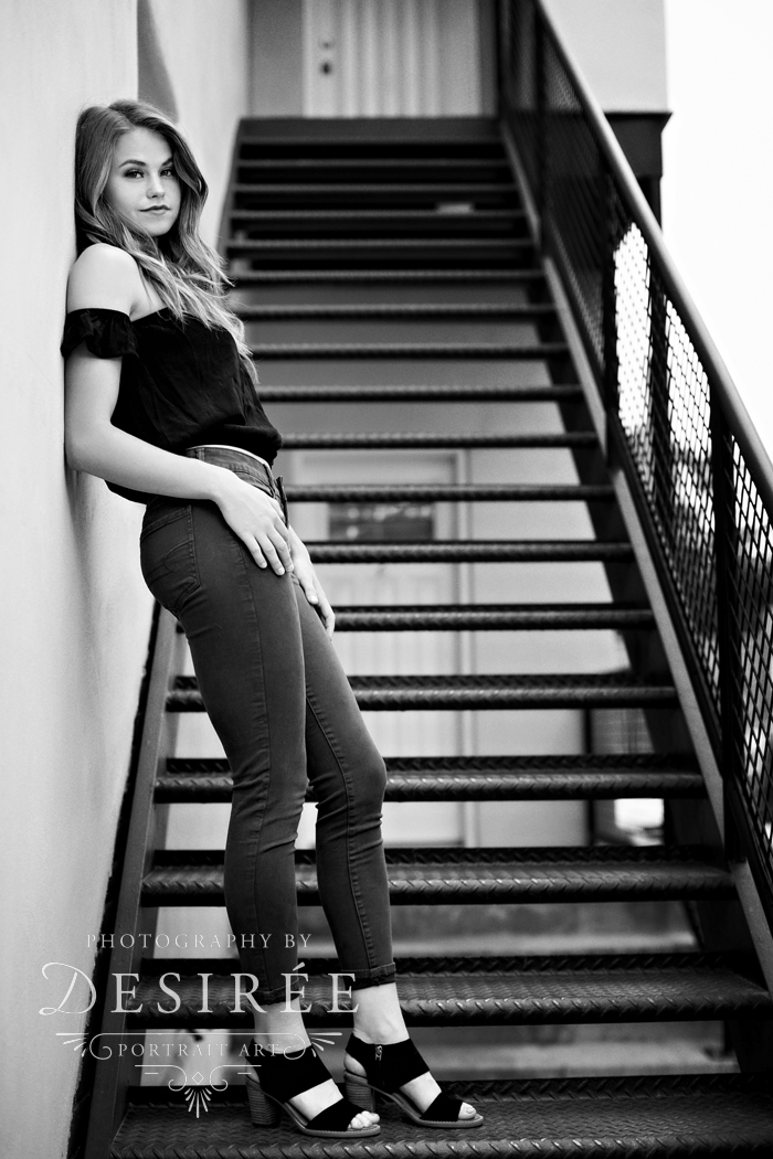 black and white high school senior girl leaning on wall