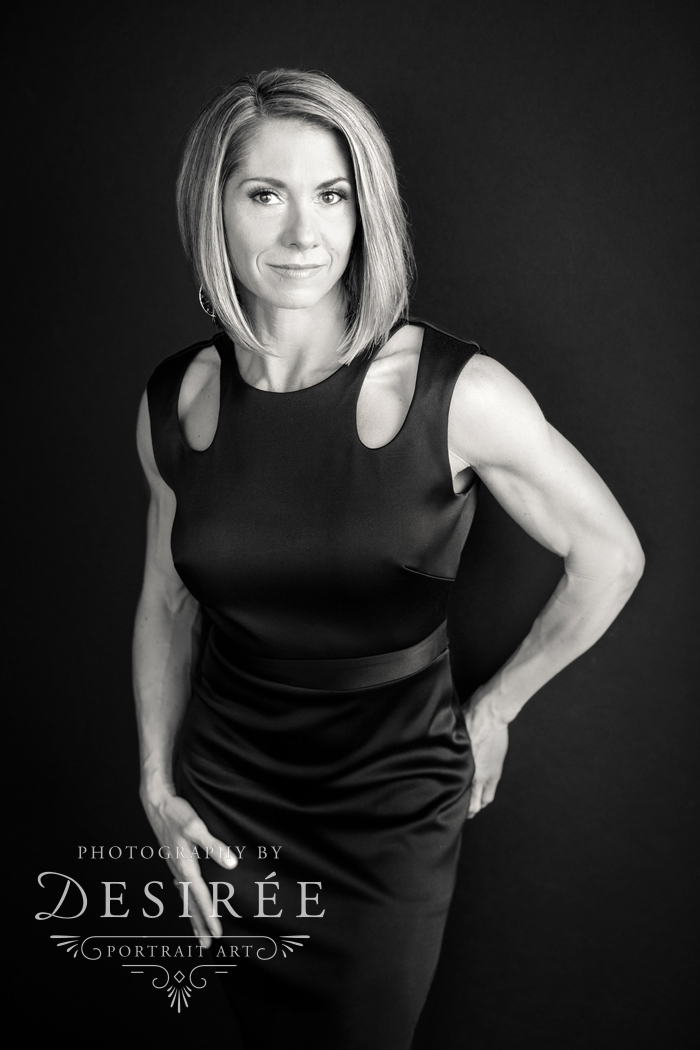 serious black and white studio portrait of beautiful woman in a black dress