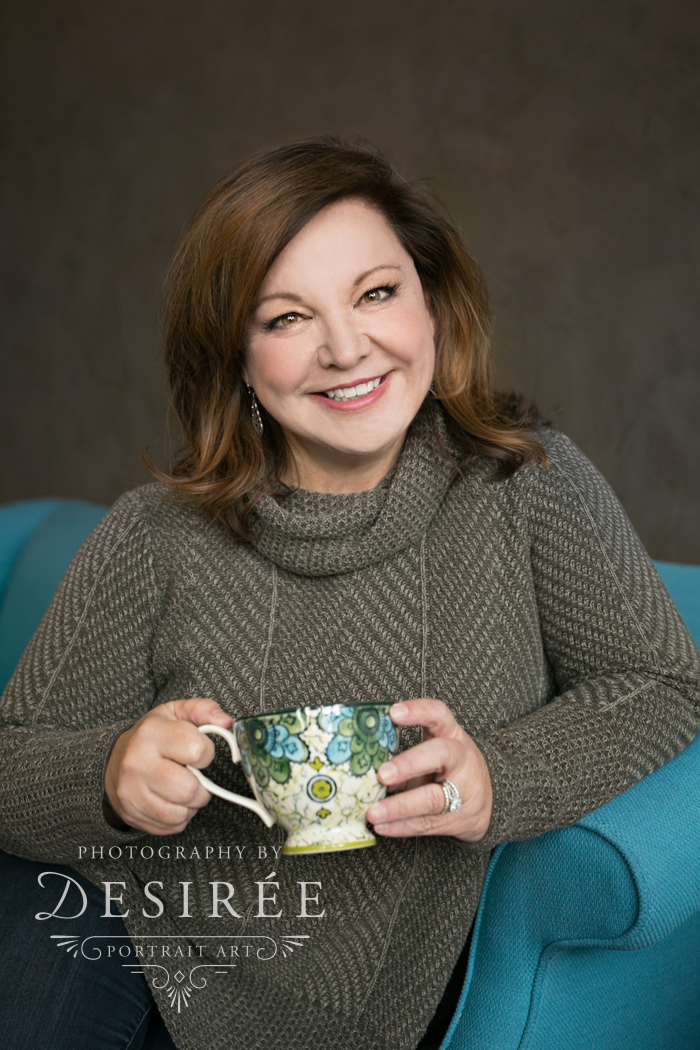 portrait of woman holding a coffee mug sitting on a couch smiling at the camera