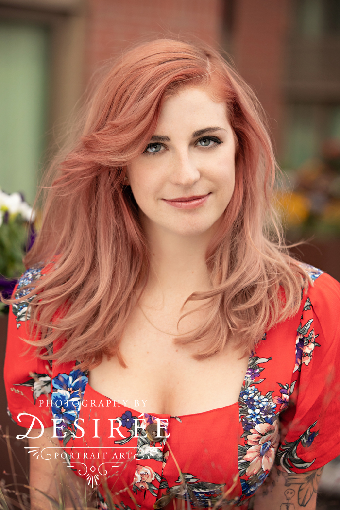 soft portrait of beautiful woman with pink hair in a red floral dress on terrace