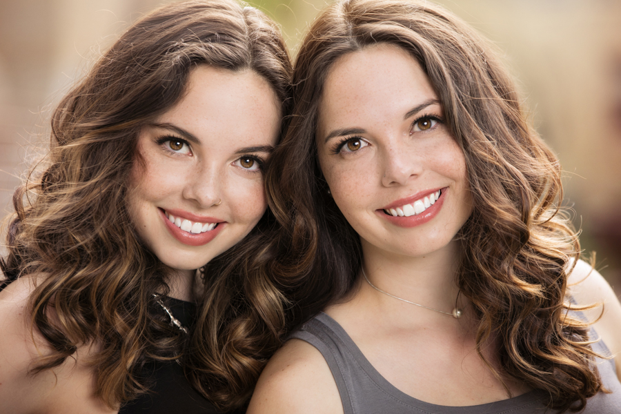 close up color portrait of young adult twin sisters smiling