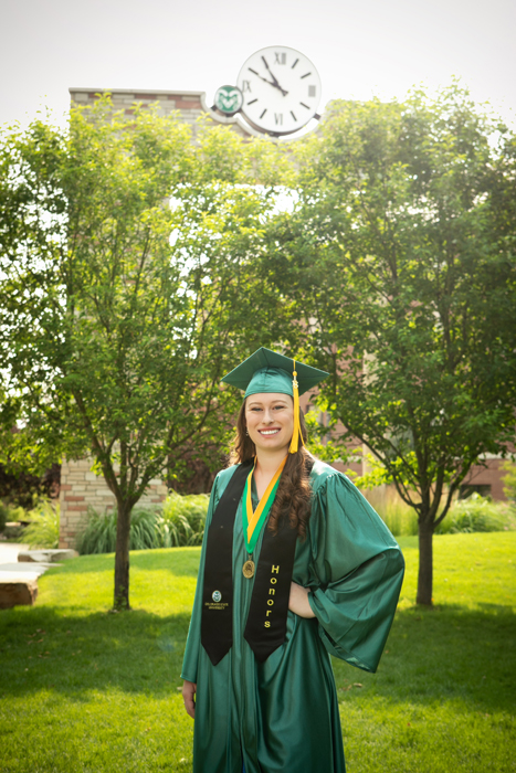 CSU grad in front of lush trees and CSU clock tower