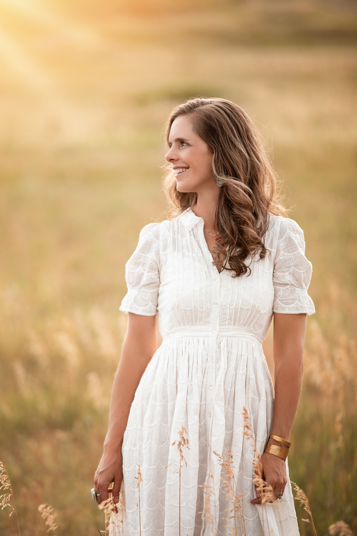lovely woman in white dress in a golden field with sun flare