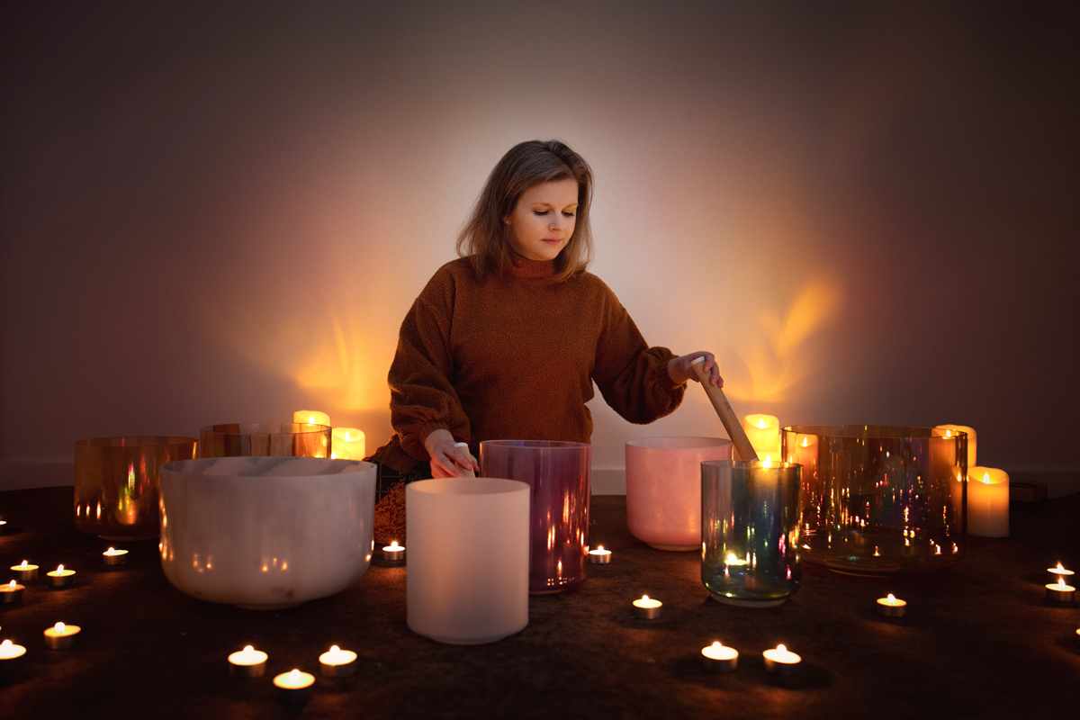 Soft, dreamy lifestyle portrait of businesswoman surrounded by crystal singing bowls and candles