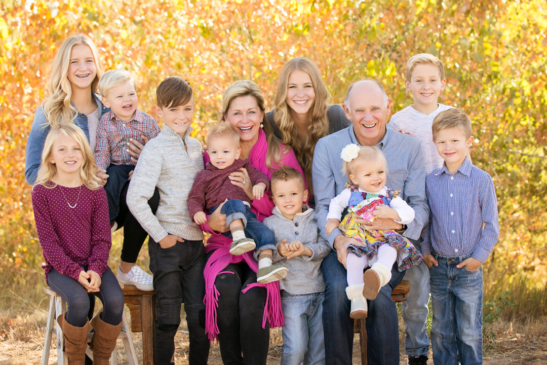 Large extended family portrait taken at The Rock Garden in Fort Collins, Colorado.  The aspen trees are the background in their perfect fall color, grandparents with all their grandkids hugging in the family image