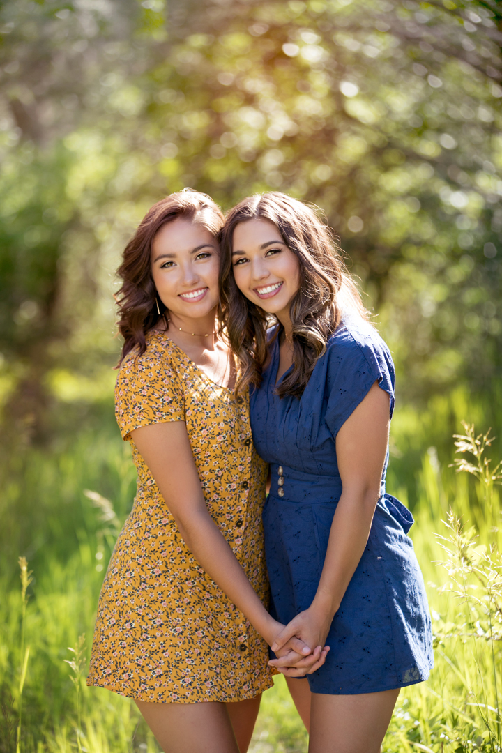 Photo of two sisters holding hands and squeezed in close together in the mountains of Colorado. By Desirée Suchy, Fort Collins Family Photographer