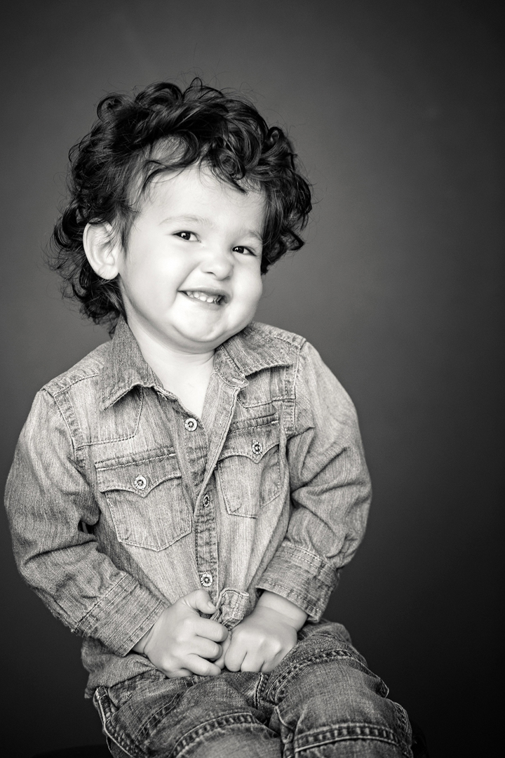 black and white studio portrait of the cutest little boy with a shit eating grin, 