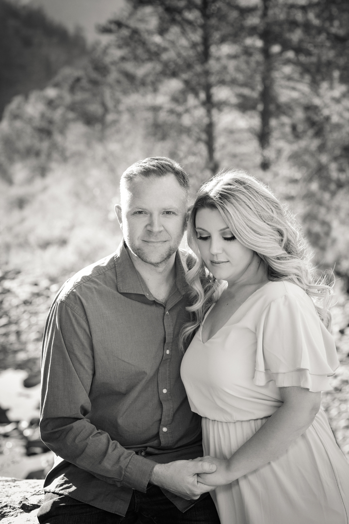 Black and white photo of a husband and wife posing in a mountain forest setting in Colorado.
