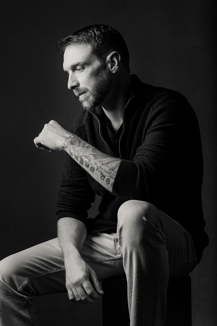 Black and white moody portrait of a man with tattoos in profile