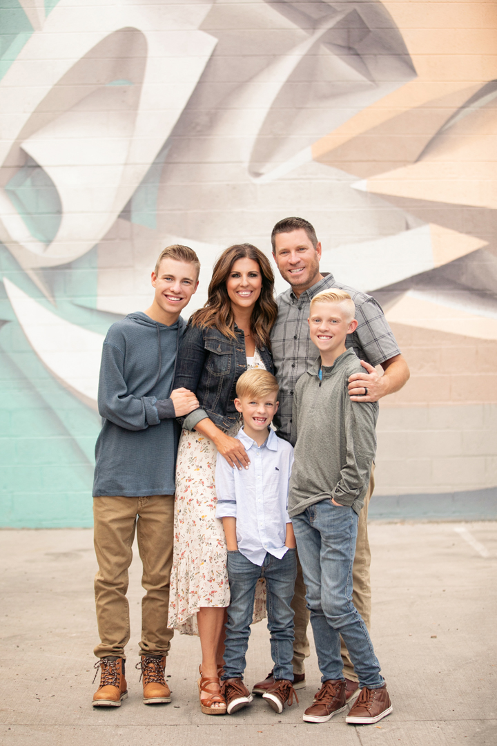 A family of five people (two parents with their three school-aged boys) posing for their family photos in front of a 3D mural in Fort Collins, CO