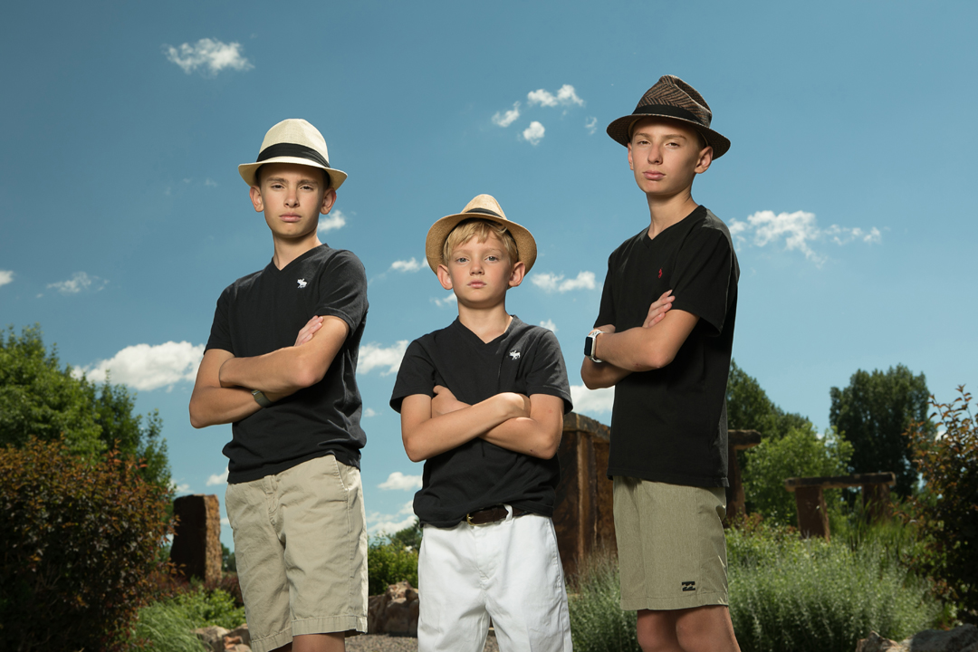 Portrait of 3 brothers with fedora's on and all blue sky behind them with cool lighting, taken at The Rock Garden in Fort Collins