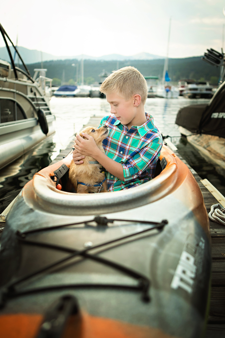Portrait of a young boy with his little dog in a Kayak on Carter Lake in Colorado, they are looking at each other