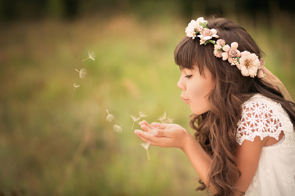 Little girl blowing dandelion pieces in a natural field setting in Colorado