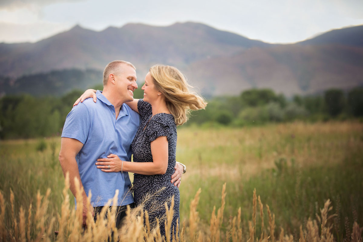 husband and wife turned towards each other laughing in a field in the flatirons in Boulder, Colorado