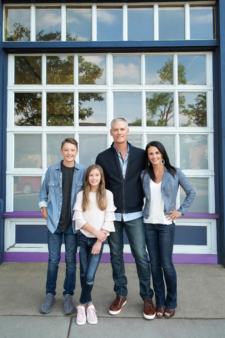 Urban family photo taken in Old Town Ft. Collins, they are all wearing denim tones in front of a Navy and glass garage door