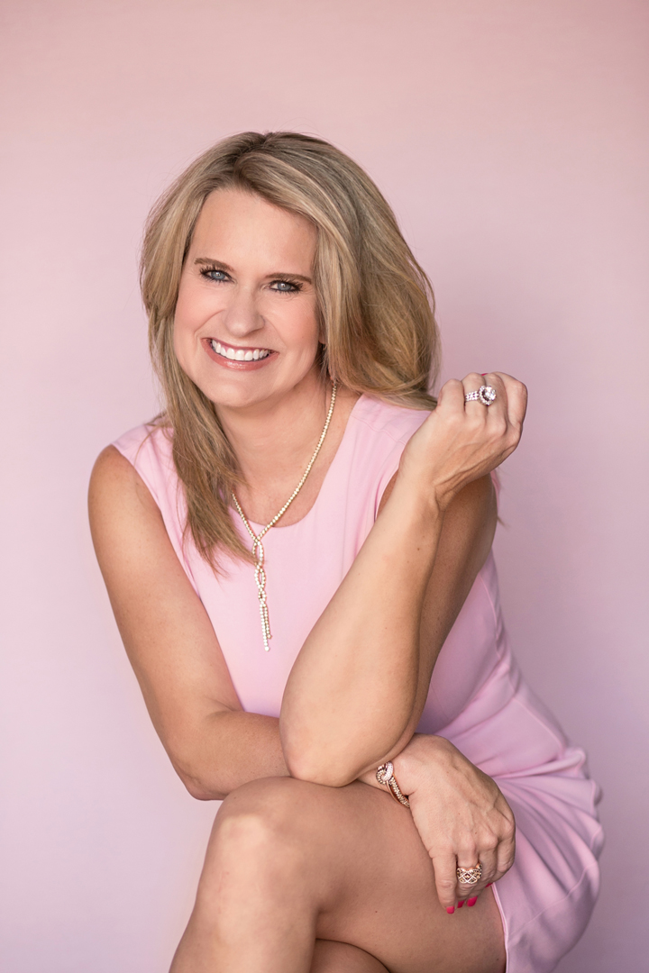 smiling photo of woman in pink dress on a pink background