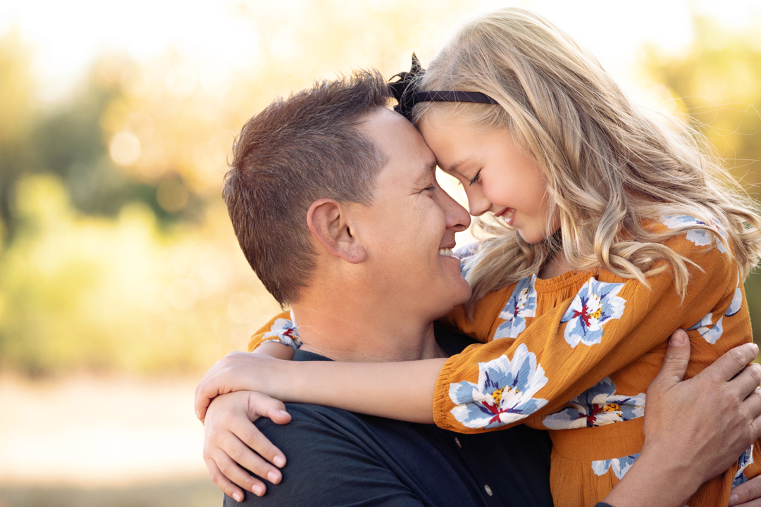 Photo taken at Legacy Park during a family photo session in Ft. Collins. Father and daughter,  forehead to forehead, softly smiling