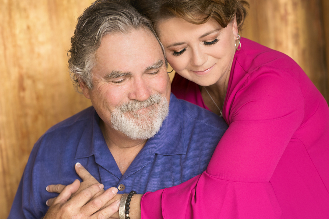 Beautiful studio portrait of an older couple with the wife leaned in and hugging her husband in such a beautiful soft way