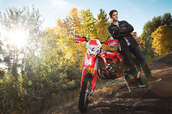 Edgy and moody posing in front of his dirt bike for his high school senior portrait