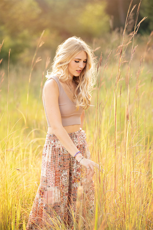 Sunny and magical high school senior portrait of a blonde female in a forest of greenery