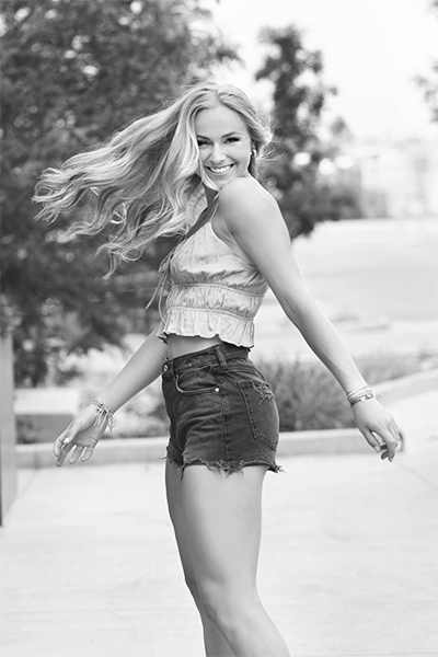 Cheerful girl twirls in her black and white high school senior portrait