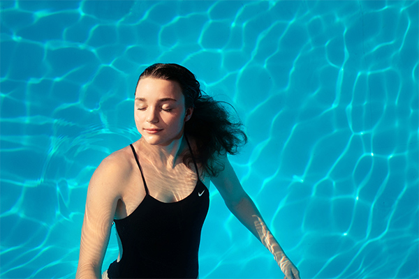 Senior girl swimmer posing in a pool for her high school senior portrait taken by Photography by Desirée