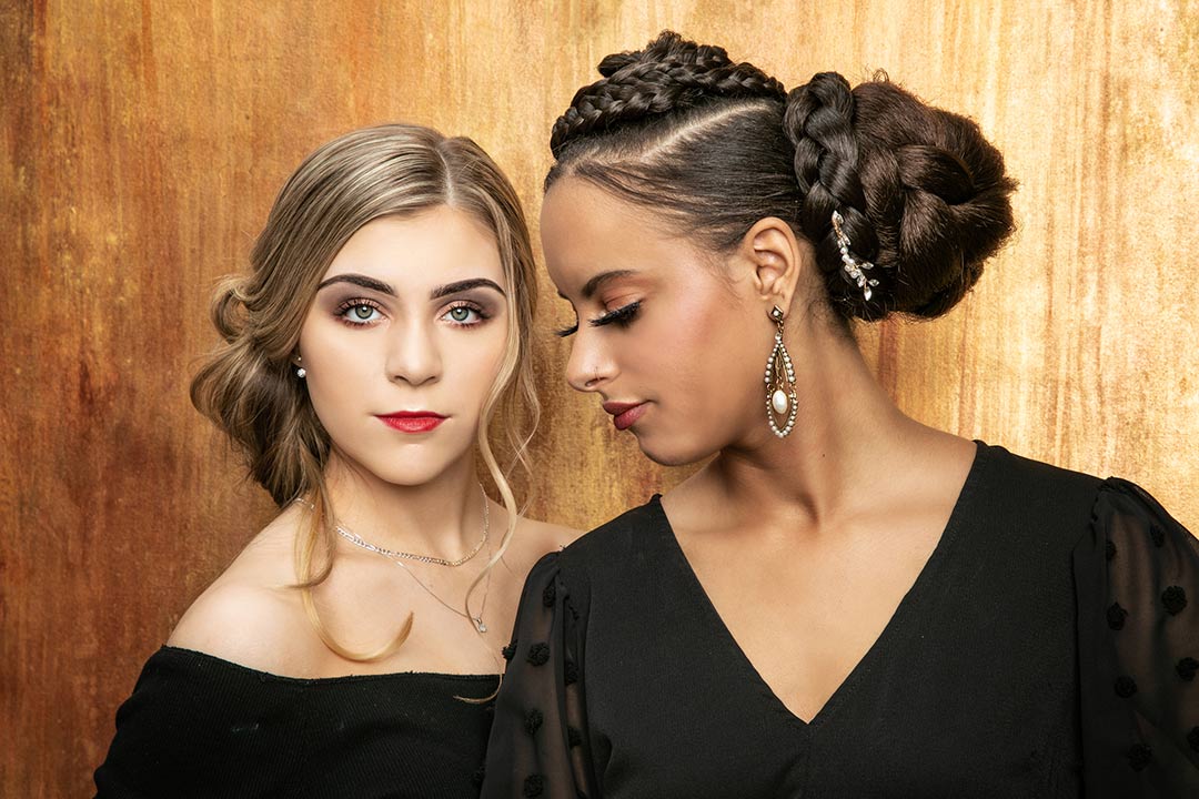 Two women dressed elegantly on a gold background posing for their business headshot with Photography by Desirée