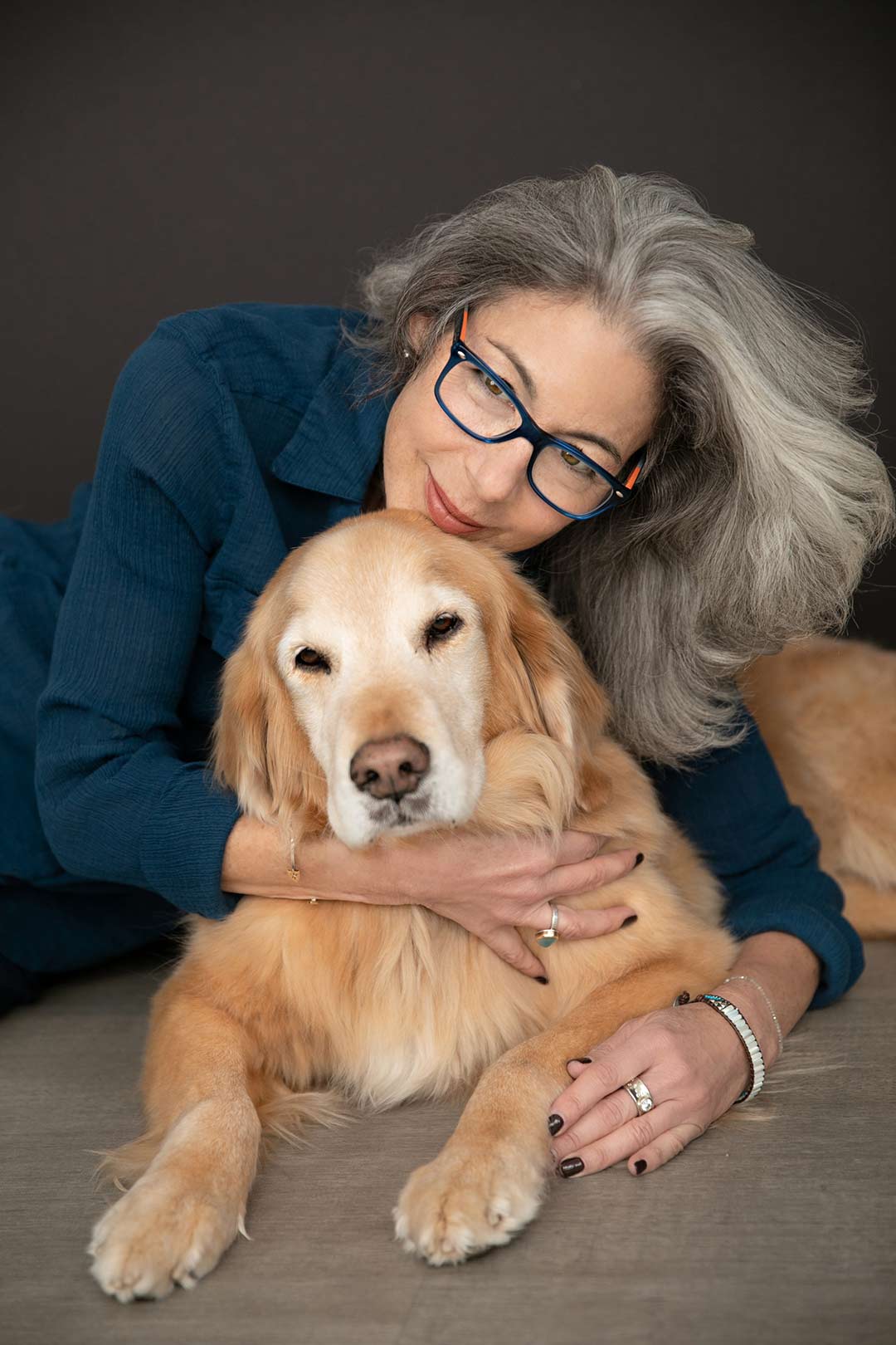 An older woman leans over her dog as her sweet personality is captured for her business portrait