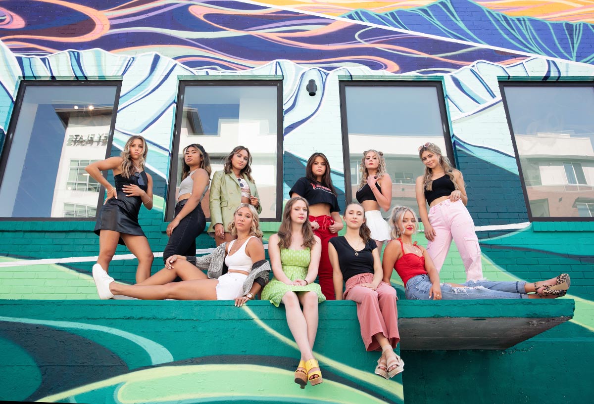 10 High school senior girl models pose in front of an edgy graffiti covered building for a group photo of Photography by Desirée's high school senior model program