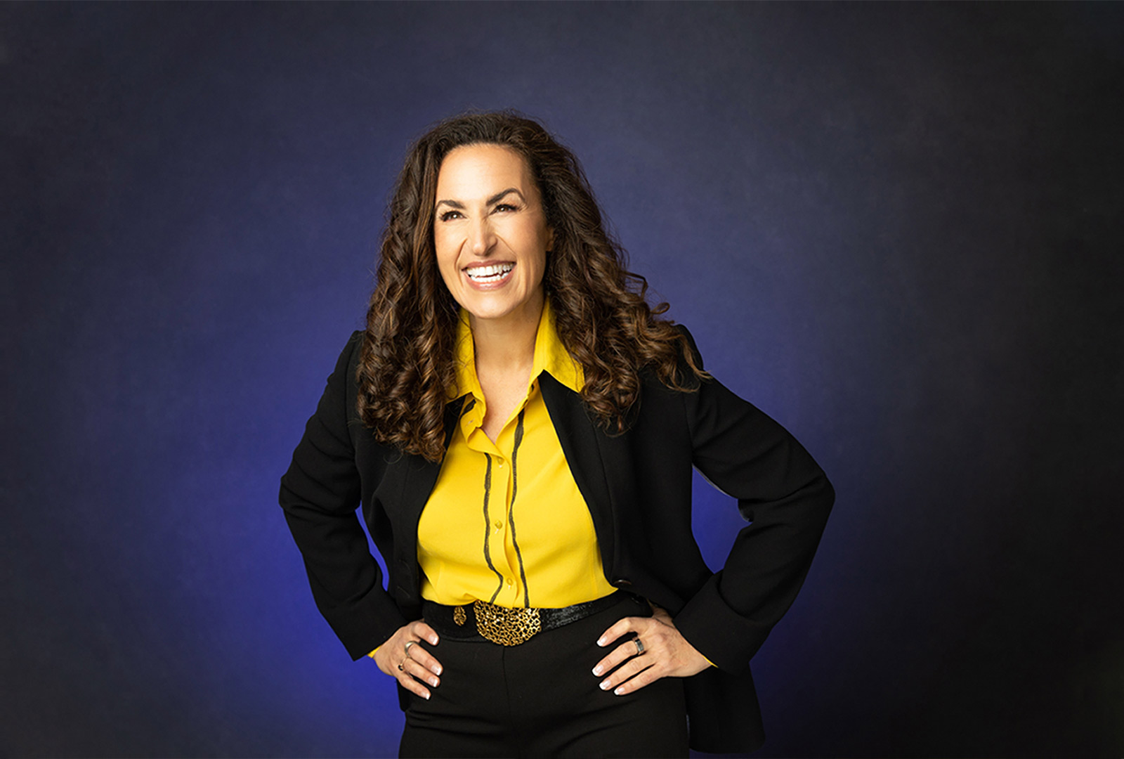 Business branding photo of a female entrepreneur smiling with her hands on her hips in a business suit